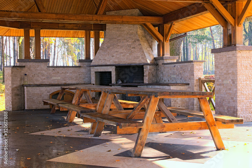 A large professional industrial  stone oven grill for cooking frying food from a stone tiled on a stone wall in the open air street. Big wooden table in the foreground