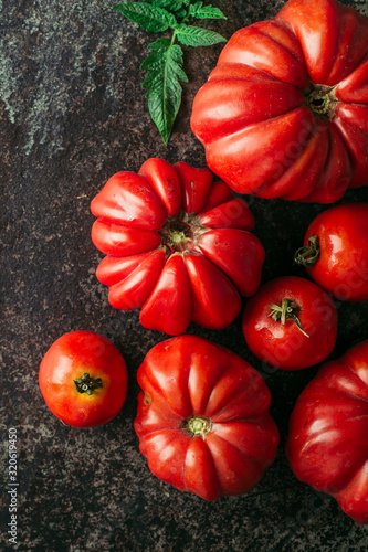 Fresh, ripe tomatoes on dark metal background.