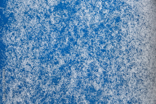 Texture of blue snowflakes on a blue background. Snow on a blue surface