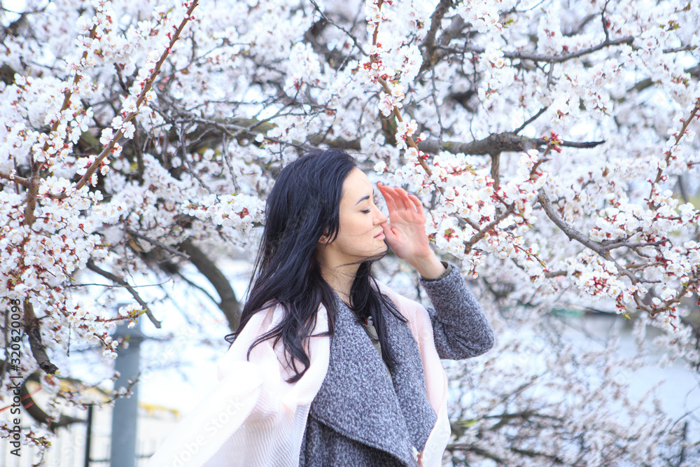 Brunette girl in a flowering cherry tree in spring Brunette girl in a flowering cherry tree in spring