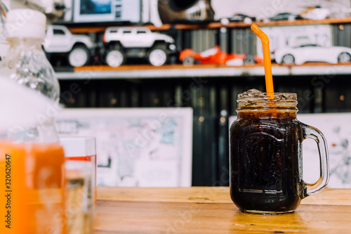 ice black coffee ,Ice coffee in a tall glass with cream poured over and coffee beans. Cold summer drink on a blue rusty background with copy space