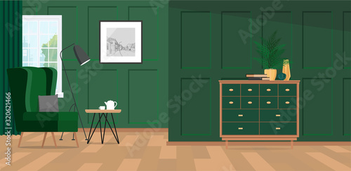 Green corner of a living room with a gray pillow on a velvet armchair next to a round, wooden coffee table.
