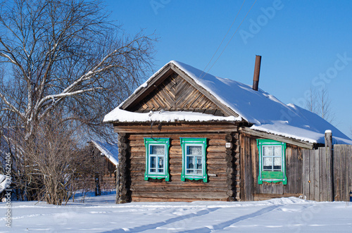 Winter landscape on a Sunny day. View of the Russian village in the snow. Authentic Wooden houses with carved frames. © Liudmila
