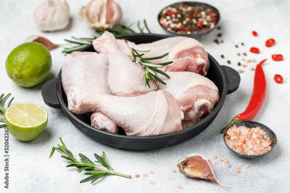 Raw uncooked chicken legs with spices and ingredients for cooking on cutting board