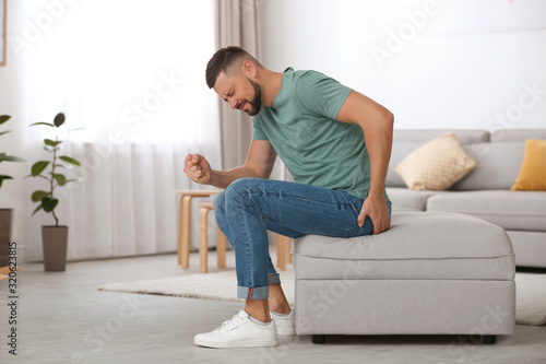 Man suffering from hemorrhoid in living room