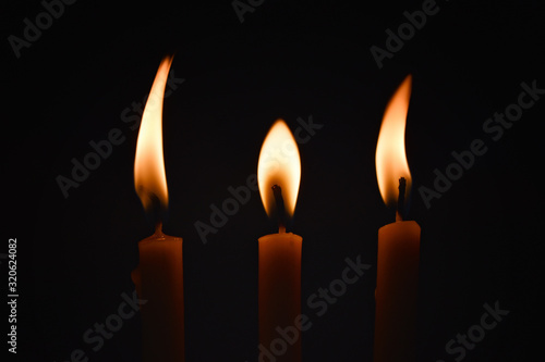 Three candles with waxed wax and dancing lights on a black background