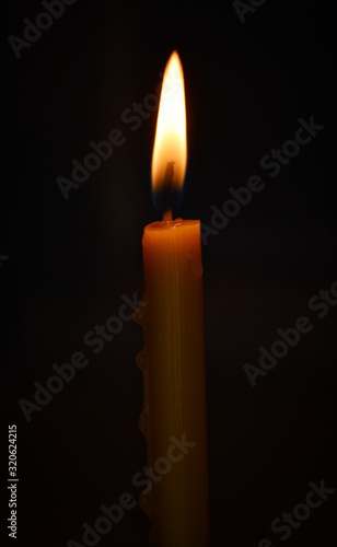Lonely church candle with a small twinkle on a black background