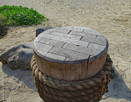 Round wooden capstan on a beach in Dubai, also acting as a coffee table.