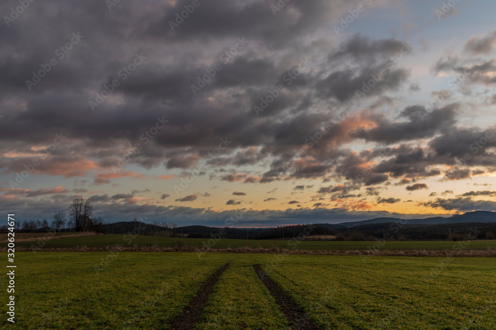 Path in color sunrise on green field near Vyhen village in south Bohemia
