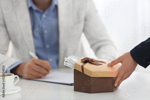 Woman giving bribe to man at table in office, closeup
