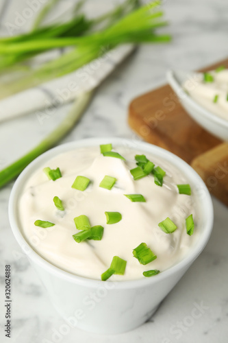 Fresh sour cream with onion on white marble table, closeup