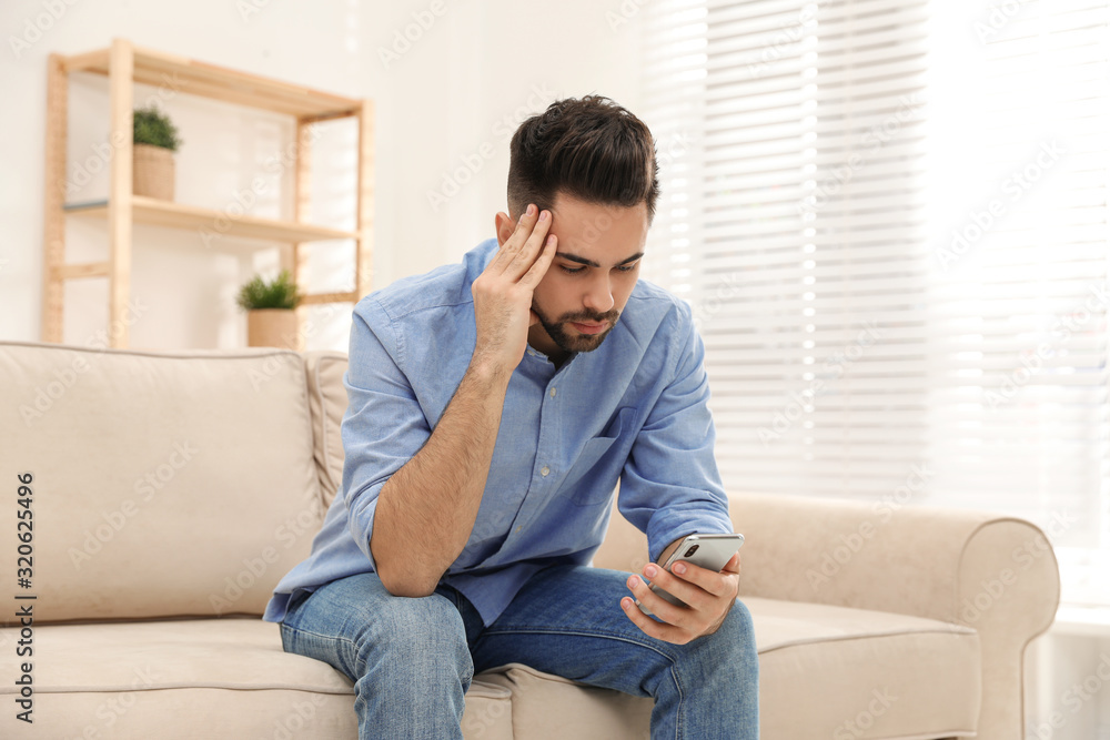 Young man addicted to smartphone on couch at home Young man addicted to smartphone on couch at home