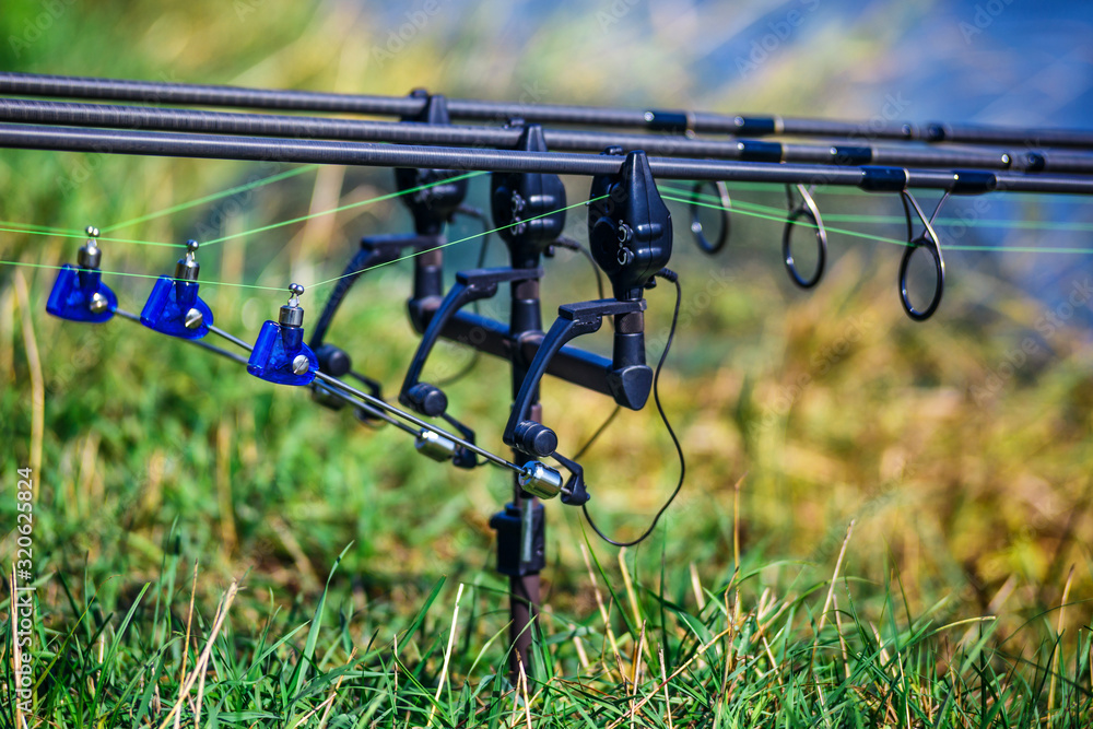 Fishing adventures, carp fishing. Carp fishing rods set up on holder with bite alarms and illuminated indicators . Professional fishing equipment