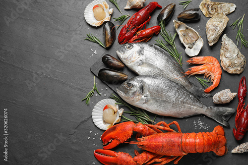 Fresh fish and different seafood on black table, flat lay. Space for text