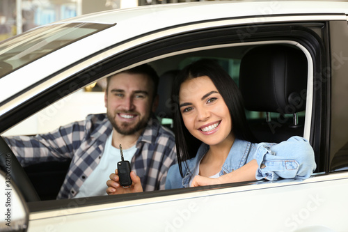 Happy couple with car key sitting in modern auto at dealership © New Africa
