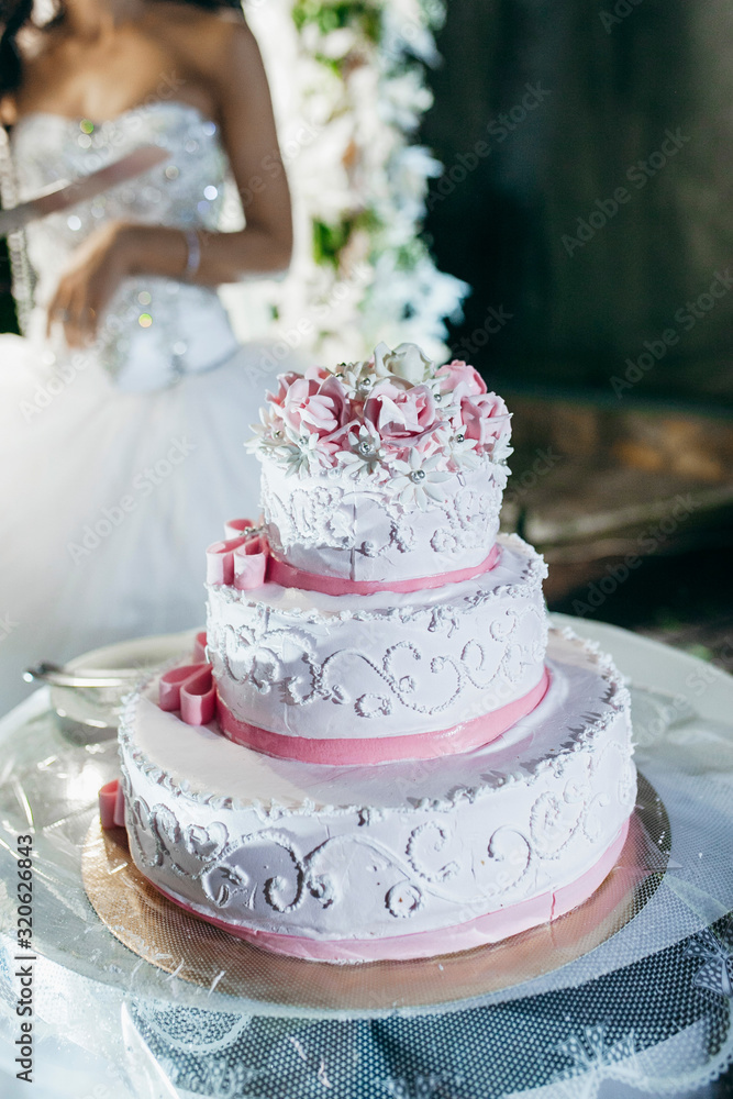 Fototapeta premium Cutting the wedding cake at evening