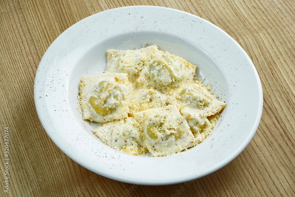 Appetizing and homemade ravioli stuffed with mushrooms or meat and ricotta cheese on a white plate on a wooden background. Italian Cuisine. Close up food Appetizing and homemade ravioli stuffed with mushrooms or meat and ricotta cheese on a white plate on a wooden background. Italian Cuisine. Close up food