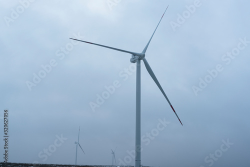  windmills in a foggy field. alternative energy.