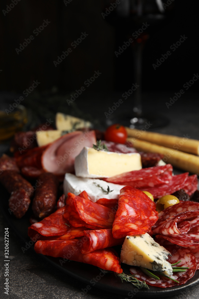 Tasty salami with other delicacies served on grey table