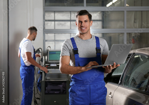Mechanic with laptop doing car diagnostic at automobile repair shop