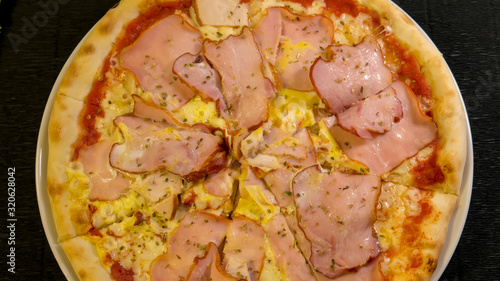 Karnos pizza with cheese, sauce and ham, bacon, smoked chicken and egg is on the table photo