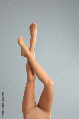 Woman wearing tights on light grey background, closeup of legs
