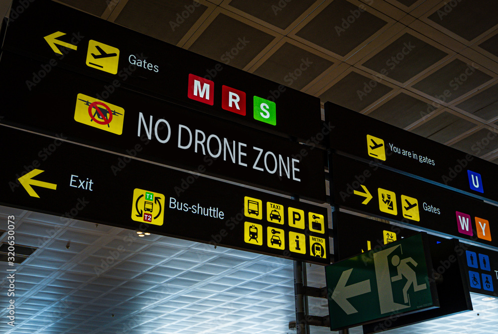 Information panel with No drone flying warning sign on it at an international airport. Drones are banned from airport aerial space, in addition to the physical collision risks that drones pose to an Information panel with No drone flying warning sign on it at an international airport. Drones are banned from airport aerial space, in addition to the physical collision risks that drones pose to an