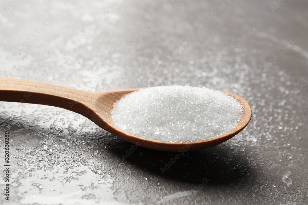 Spoon of white sugar on marble table, closeup Spoon of white sugar on marble table, closeup