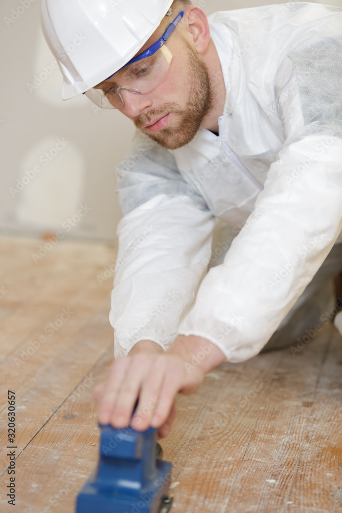 male tradesman sanding wooden floor
