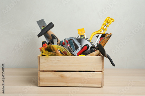 Crate with different carpenter's tools on wooden table photo