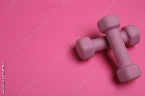 Modern dumbbells on pink background. Space for text