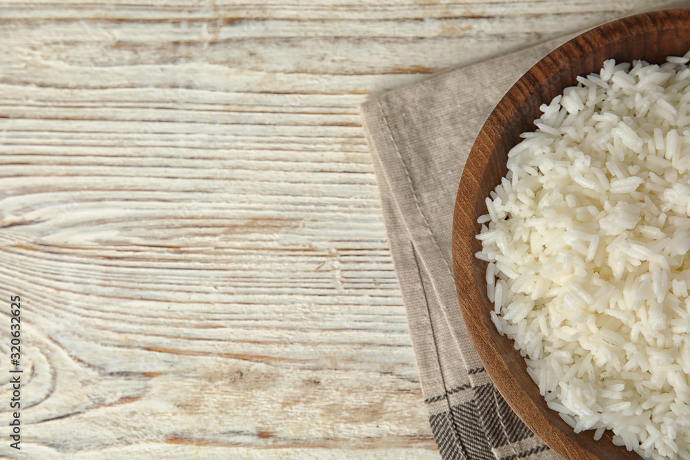Bowl with tasty cooked rice on white wooden table, flat lay. Space for text Bowl with tasty cooked rice on white wooden table, flat lay. Space for text
