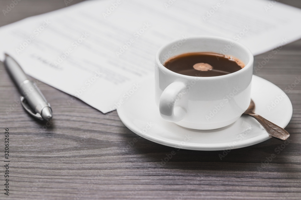 contract signing concept, close-up cup of coffee, silver pen and empty paper sheet of agreement between two counterparties on grey wooden table as background, selective focus contract signing concept, close-up cup of coffee, silver pen and empty paper sheet of agreement between two counterparties on grey wooden table as background, selective focus