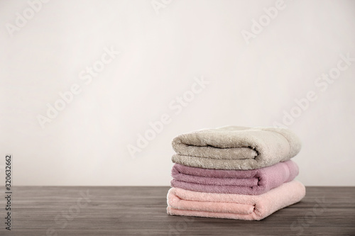 Stack of fresh towels on grey wooden table. Space for text