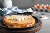 Delicious thin pancakes with butter on grey table, closeup