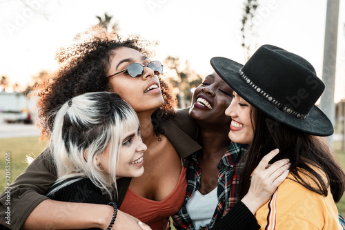 Group portrait of diverse young women wearing clothes in hipster style looking at each other with smiles and hugging together   photo