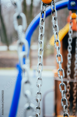 Metal chains with a large ring for a children's swing on the street in macro