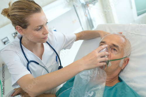 female doctor applying oxygen mask on senior patient photo