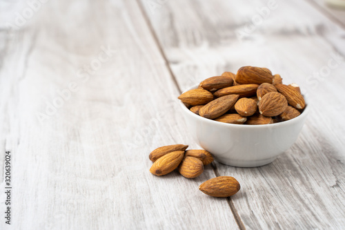 Almonds seed in the white bowl on wood table photo