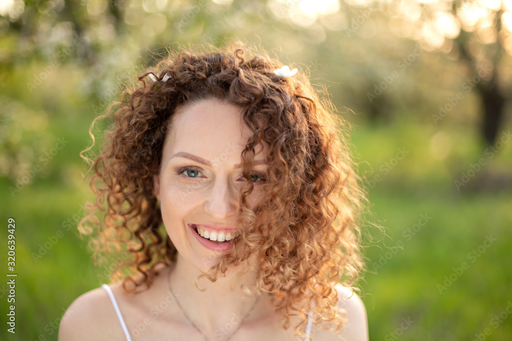 Close up portrait of young smiling attractive woman with curly hair in green flowering spring park. Pure emotions. Close up portrait of young smiling attractive woman with curly hair in green flowering spring park. Pure emotions.
