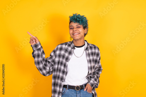 young afro american girl isolated on yellow background pointing by hand