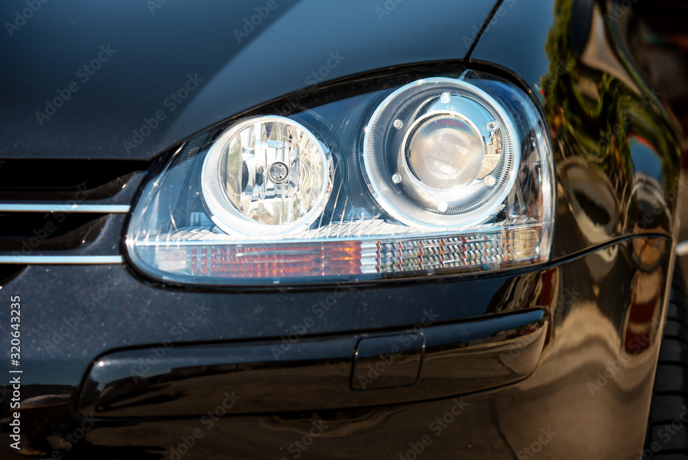 Car headlight with shallow depth of field. - obrazy, fototapety, plakaty 