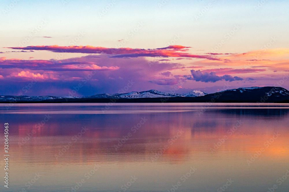 Beautiful sunset over Lake Yellowstone with reflection in water and snow capped mountains in the background