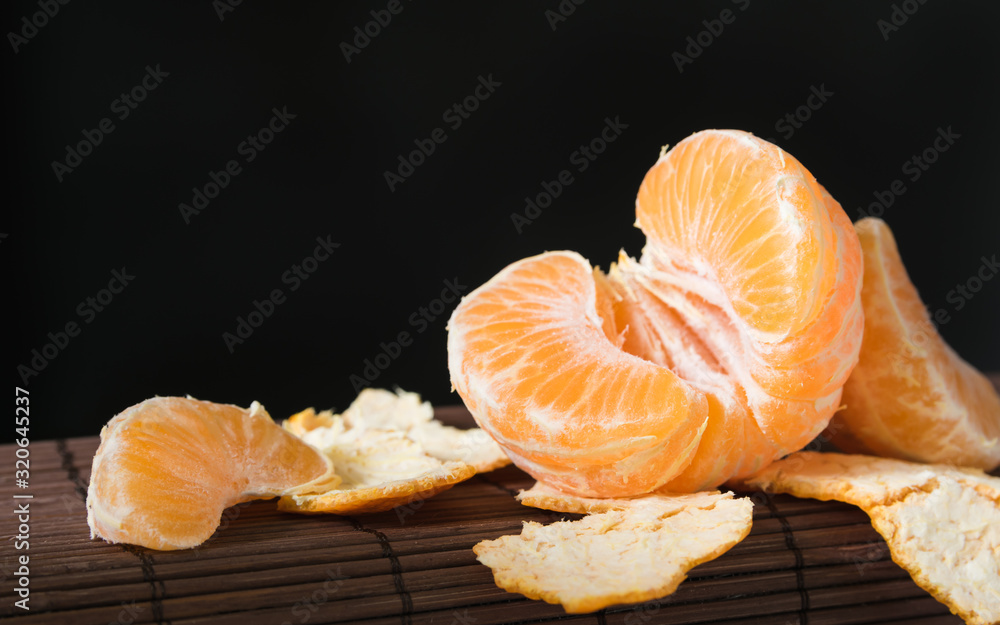 still life, slices of ripe juicy mandarin on a black background close-up