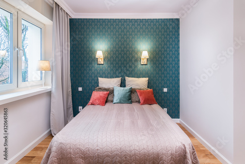 Cozy bedroom interior with colorful pillows and stylish wallpaper