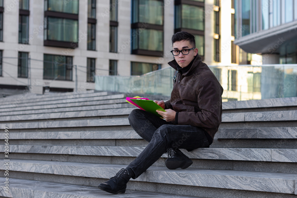 Obraz premium young male Asian student sitting on steps of University read books and thought