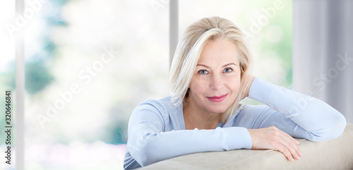 Beautiful business woman smiling friendly and looking in camera near the window in office. Happy woman's face closeup. Selective focus.
