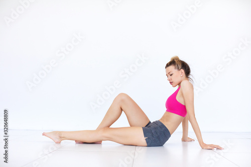 Young beautiful woman after workout sits on the floor in the studio.