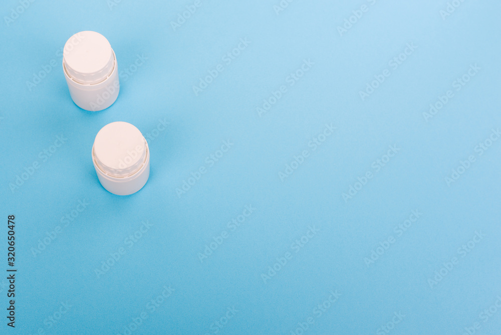 Small white plastic jars with pills on a blue background. Pharmacy medicines to treat a person. Pharmacy preparations. Medical bottle. Small white plastic jars with pills on a blue background. Pharmacy medicines to treat a person. Pharmacy preparations. Medical bottle.