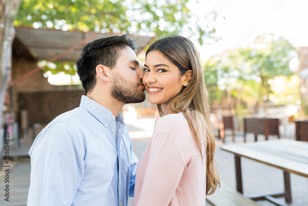Man Kissing Happy Girlfriend Outside Cafe Man Kissing Happy Girlfriend Outside Cafe